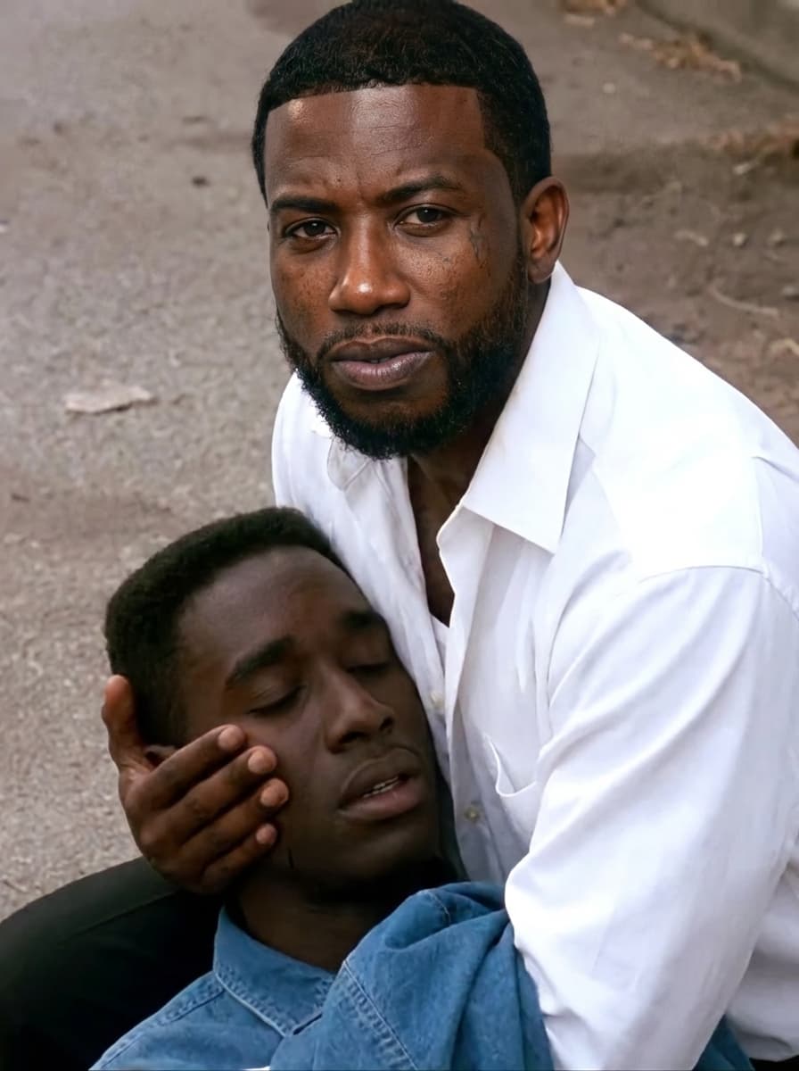 Use the provided image as the base reference.

🎯 CORE TASK:

Perform a high-precision face and identity swap on the man wearing the white shirt.

🧍‍♂️ SUBJECT TRANSFORMATION:
Replace the face of the man in the white shirt with a realistic version of Gucci Mane (rapper)
Maintain:
Same pose (holding the other person)
Same body position and angle
Same clothing (white shirt — DO NOT change outfit)
Same emotional intensity and expression
FACIAL DETAILS:
Apply Gucci Mane’s:
Facial structure
Skin tone
Beard/goatee
Hairline
Expression should match the scene:
distressed, emotional, intense
⚠️ STRICT RULES:
DO NOT change:
Background or environment
Lighting or shadows
Camera angle or framing
The second person in the image
Preserve:
Original cinematic realism
Natural blending of skin tones and lighting
Emotional tone of the scene
🎬 STYLE:
Realistic movie still
Natural lighting
Slight film grain
No cartoon or AI distortion
