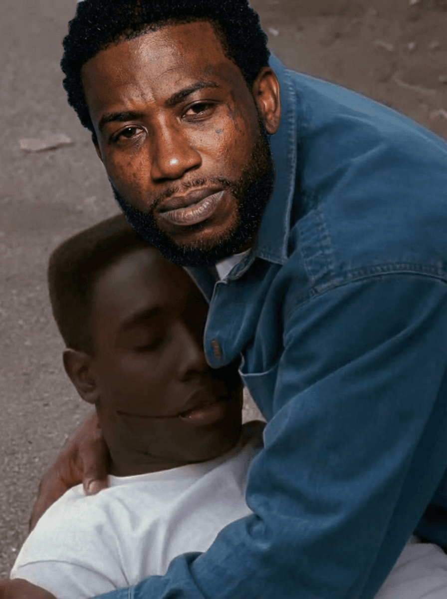Use the provided image as the base reference.

🎯 CORE TASK:

Perform a high-precision face and identity swap on the man wearing the white shirt.

🧍‍♂️ SUBJECT TRANSFORMATION:
Replace the face of the man in the white shirt on ground with a realistic version of Gucci Mane (rapper)
Maintain:
Same pose (holding the other person)
Same body position and angle
Same clothing (white shirt — DO NOT change outfit)
Same emotional intensity and expression
FACIAL DETAILS:
Apply Gucci Mane’s:
Facial structure
Skin tone
Beard/goatee
Hairline
Expression should match the scene:
distressed, emotional, intense
⚠️ STRICT RULES:
DO NOT change:
Background or environment
Lighting or shadows
Camera angle or framing
The second person in the image
Preserve:
Original cinematic realism
Natural blending of skin tones and lighting
Emotional tone of the scene
🎬 STYLE:
Realistic movie still
Natural lighting
Slight film grain
No cartoon or AI distortion
