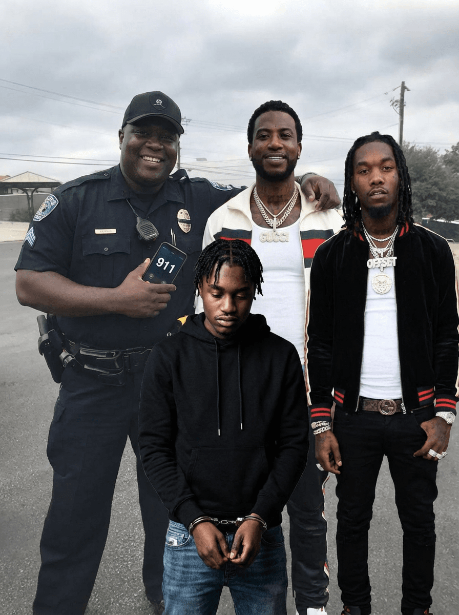 Use the provided image as the base reference. Maintain the exact same environment lighting, camera angle, pose, outfit structure, and composition from the original image. Replace the original subject with OFFSET THE RAPPER AN GUCCI MAN WITH A BLACK FAT COP wearing outfits attached HOLDING A PHONE WITH 911 ON IT WITH LIL TJ IN FRONT TO HIM IN HANDCUFFS

