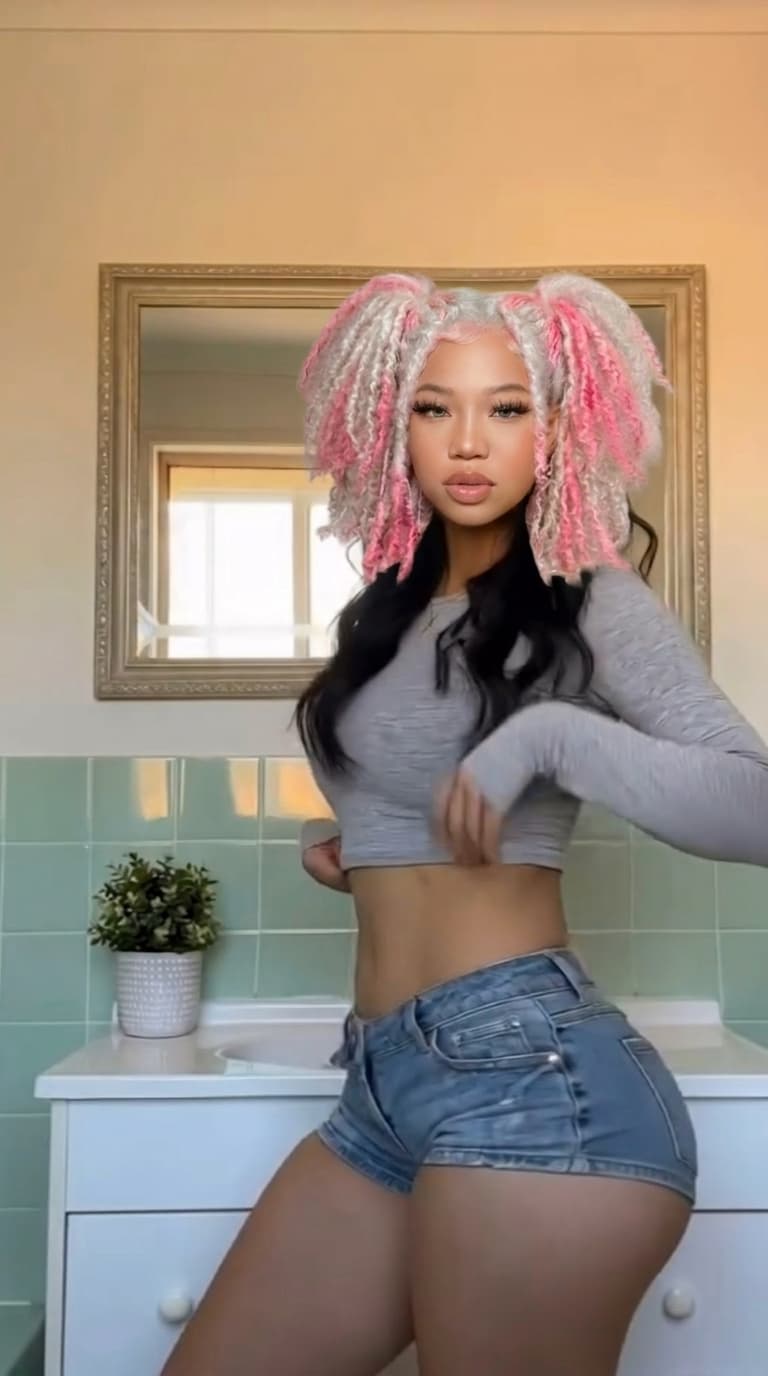 Replace the face, skin tone, and hairstyle of the black hair woman with the pink and white hair woman reference person, while keeping the original pose, body, outfit, lighting, and background unchanged. Ensure the result looks natural, realistic, and seamlessly blended.