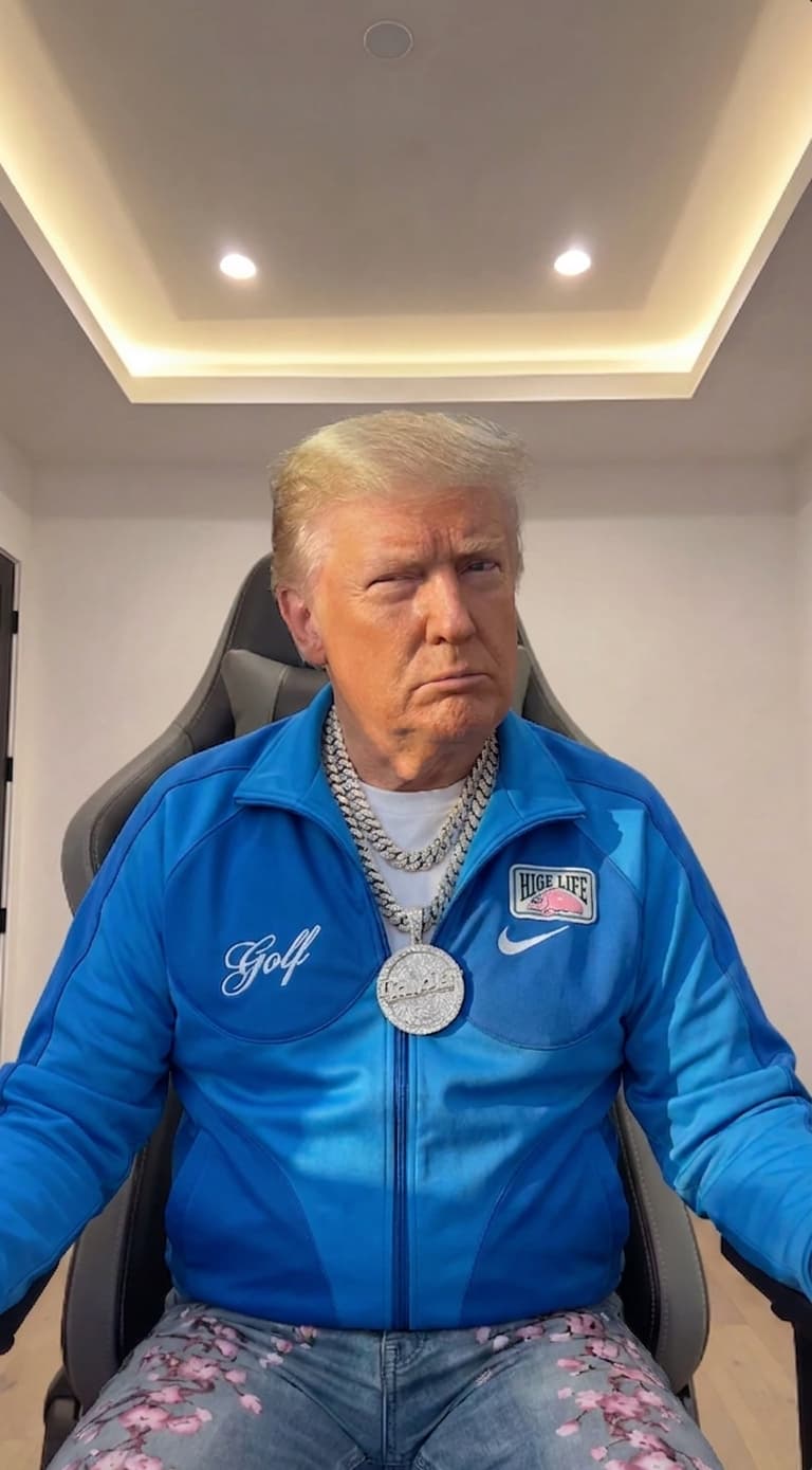 Donald Trump seated in a modern black gaming chair, wearing a vibrant BLUE Nike tracksuit jacket with “Golf” embroidered in cursive on the left chest and a “High Life” beer patch on the right, layered over a plain white t-shirt, accessorized with multiple thick silver chains and a large circular medallion pendant, paired with light-wash denim jeans featuring a pink cherry blossom floral print; his expression is stern and slightly skeptical, eyes narrowed, lips pursed, head tilted slightly to his right; the setting is a clean, minimalist modern room with white walls and recessed ceiling lighting casting soft shadows, two bright spotlights visible in the tray ceiling above; lighting is even and studio-like, highlighting the sheen of the BLUE tracksuit fabric and metallic jewelry; composition is a medium close-up centered on Trump from the waist up, with shallow depth of field slightly blurring the background; colors are dominated by BLUE, silver, and denim blue with warm ambient lighting; ultra-detailed, photorealistic, high-resolution, 8K, sharp focus, cinematic lighting, realistic skin texture, accurate facial likeness, professional portrait style.