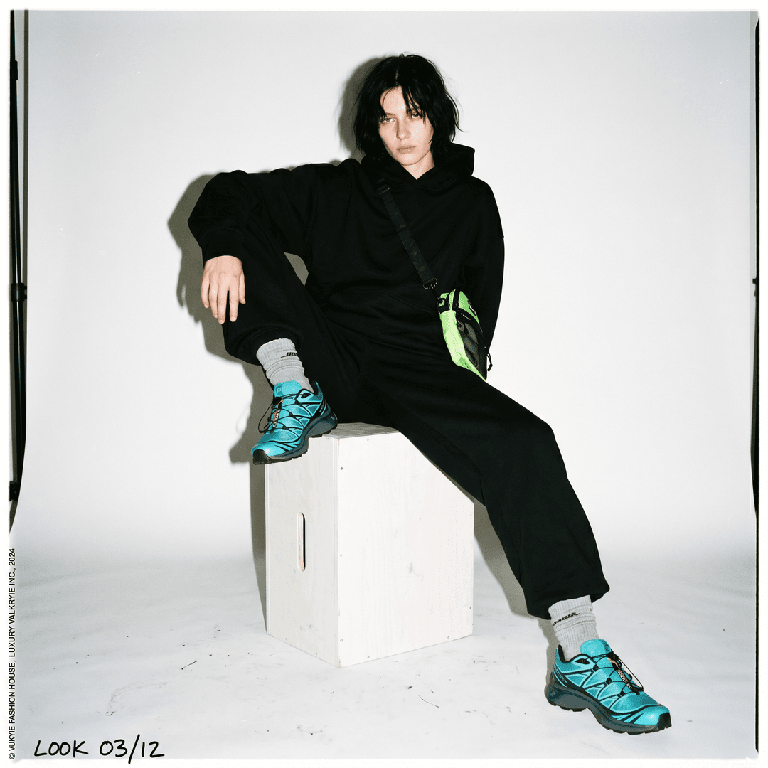 Idea: expensive fashion campaign pretending to be low effort
Clothing Style: oversized monochrome streetwear set with contrasting accessories and bold sneakers
Camera Angle: ultra-clean studio shot with slightly awkward framing and direct flash
A minimalist white seamless studio fashion image featuring the uploaded clothing styled with intentional awkwardness. The subject sits weirdly on a white cube with legs spread naturally and shoulders slouched unevenly. Hard direct flash creates strong shadows behind the subject like early 2000s editorial photography. Slight overexposure on skin highlights and realistic facial texture. Outfit styling should feel expensive but emotionally detached. Tiny imperfections everywhere: wrinkled socks, loose hoodie strings, messy hair strands, natural posture imbalance. Fashion-editorial meets internet realism.