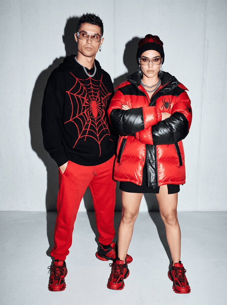 aggressive direct flash fashion photograph of stylish subjects posing in coordinated spider-themed luxury streetwear, oversized hoodies, graphic knitwear, bold red and black accessories, designer sneakers and novelty eyewear, emotionally detached expressions with awkward editorial body language, clean minimal interior background with strong flash shadows and glossy fabric highlights, symmetrical composition with low-angle framing, modern hypebeast campaign aesthetic, shot on 35mm lens