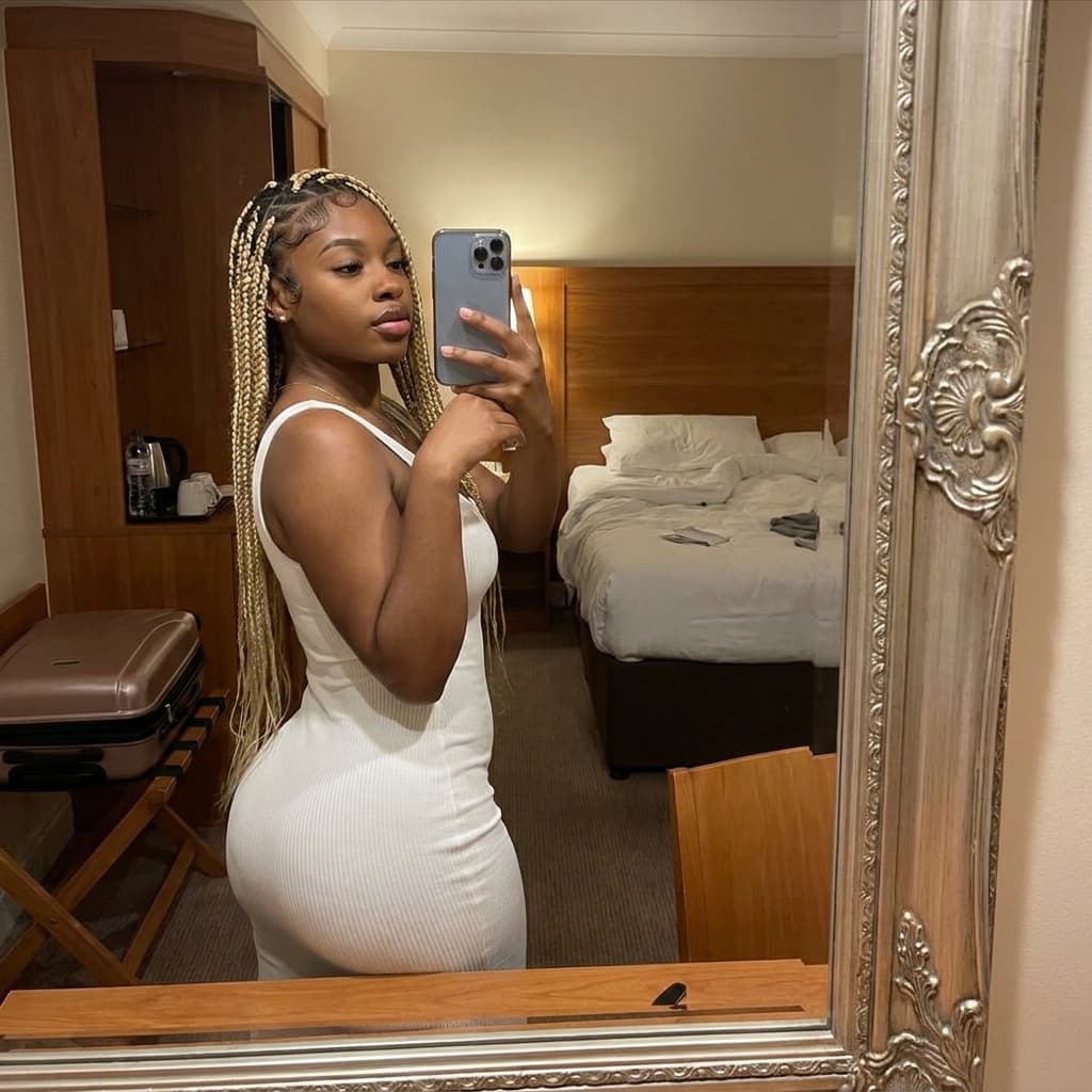 A young ebony woman in her 20s, plump lips, long blonde hair with hair edges, curvy body, thick thighs, plump ass, selfie pov mirror in hotel. Wearing bodycon white dress